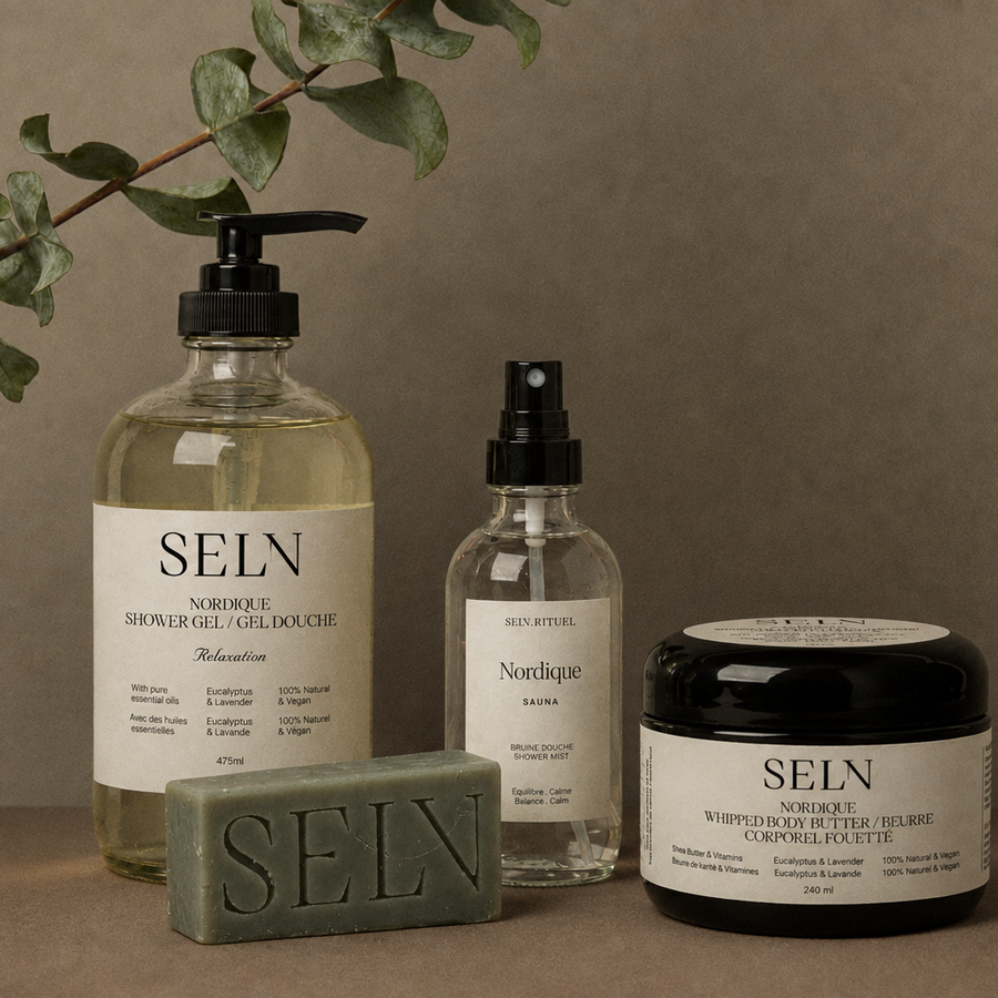 Le Quatuor Douche Nordique de Selv Rituel : gel douche, savon en barre, bruine de douche et beurre corporel fouetté, avec une branche d’eucalyptus