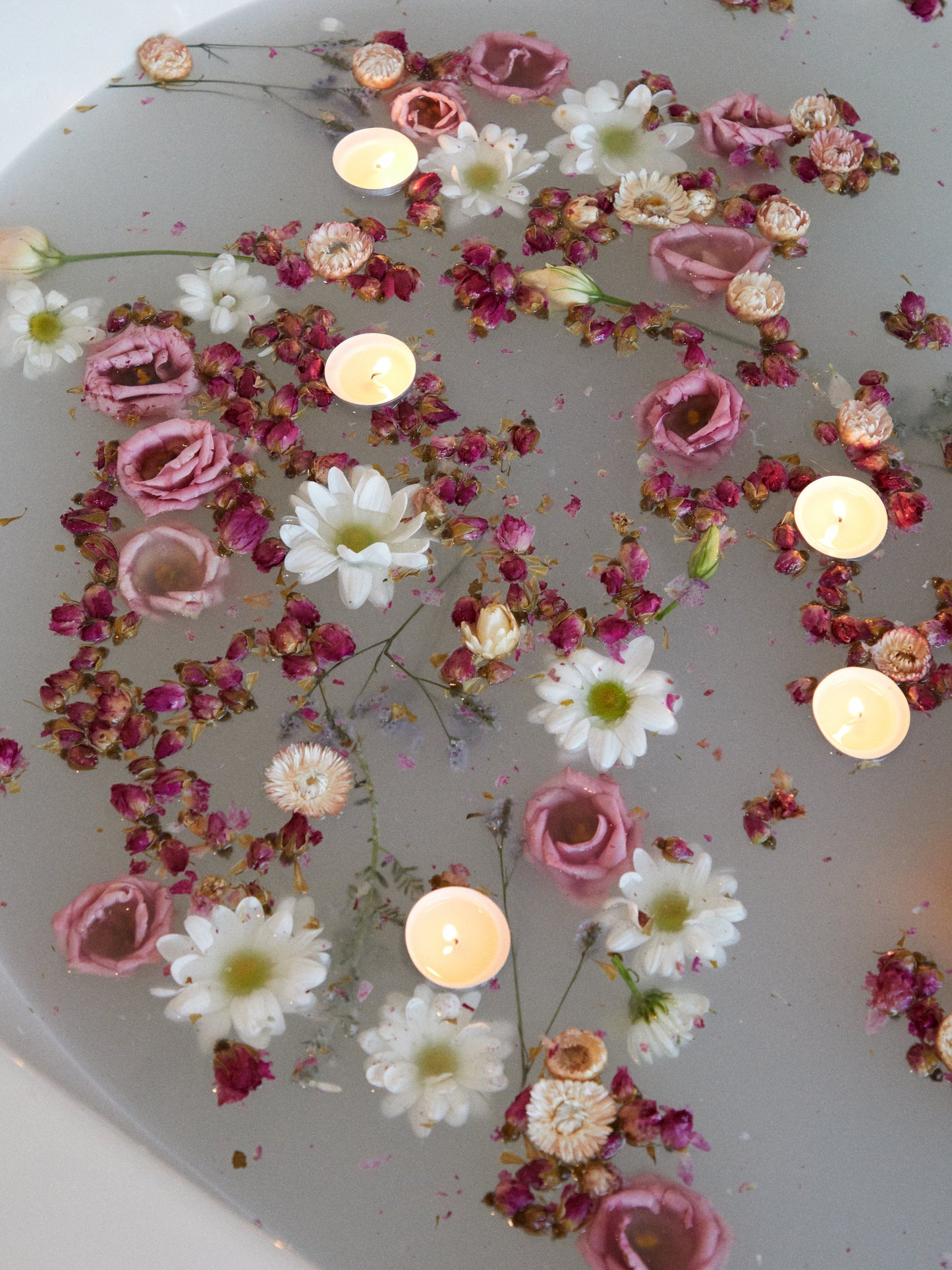 Bain parsemé de fleurs roses et blanches et de petites bougies