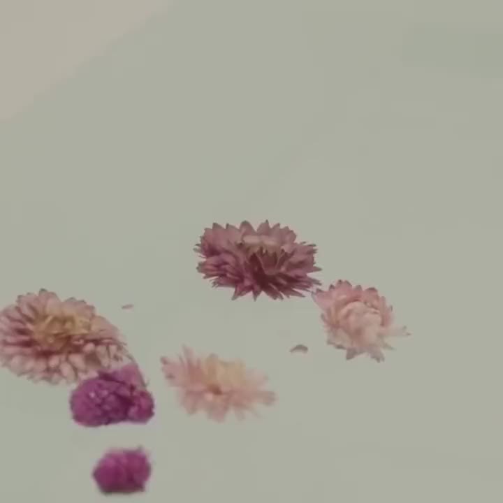 Fleurs séchées roses et mauves flottant à la surface de l'eau du bain